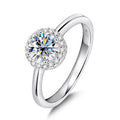 Bee-Bees 1ct round brilliant cut moissanite engagement ring in 925 sterling silver with 18k white gold plating and halo of small stones.
