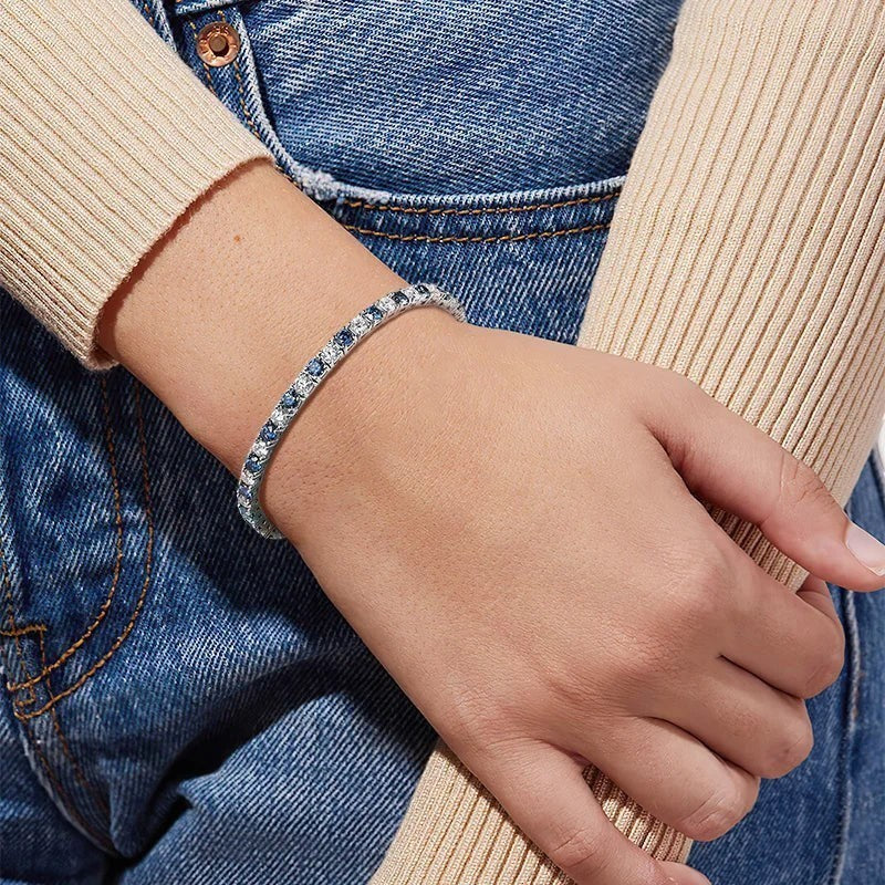 Bee-Bee's blue moissanite and clear stone tennis bracelet on a woman's wrist, crafted from S925 sterling silver with 18k white gold plating.
