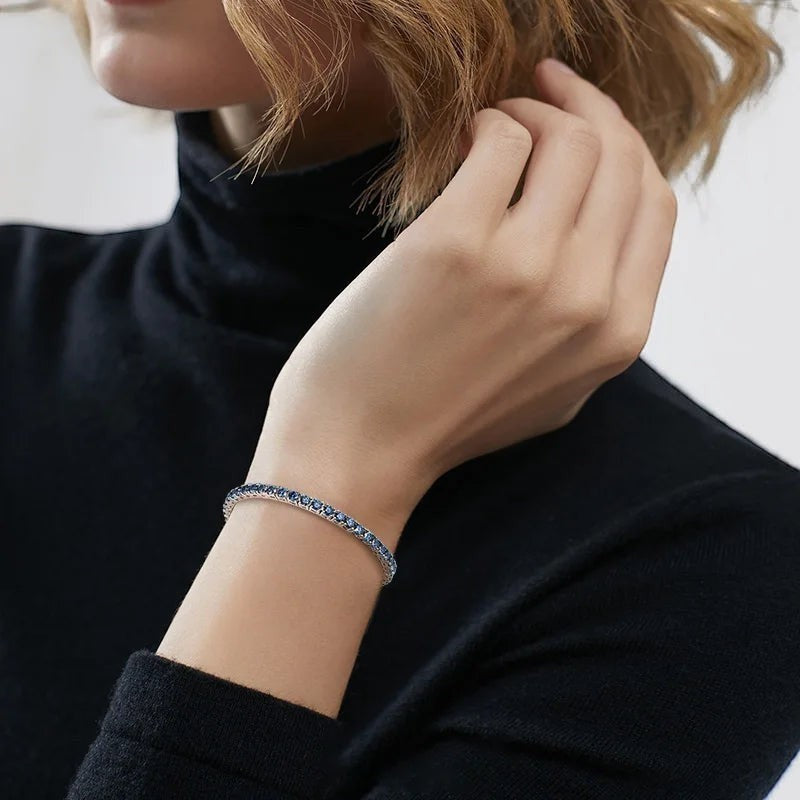 Bee-Bees blue moissanite tennis bracelet on a woman's wrist, crafted from S925 sterling silver with 18k white gold plating.