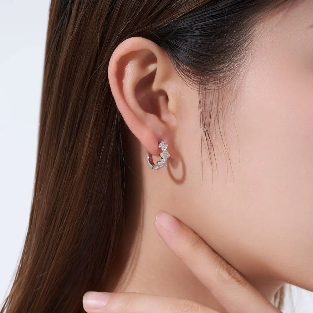 Bee-Bees four leaf clover moissanite huggie earrings in 925 sterling silver worn on a woman's ear