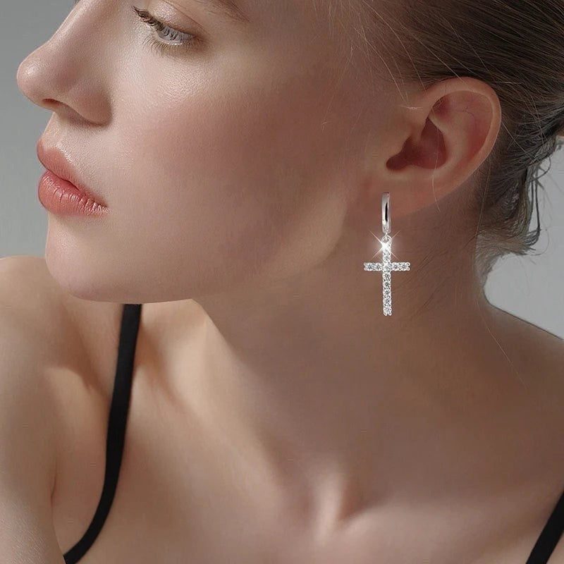 Bee-Bee's sterling silver hoop earrings with a dangling cross pendant encrusted with sparkling moissanite stones.