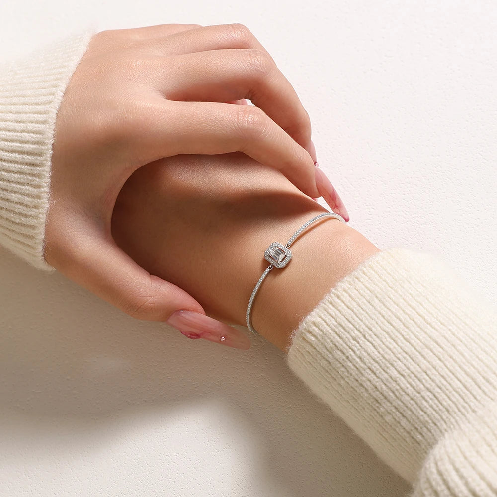 Bee-Bees emerald cut moissanite tennis bracelet in 925 sterling silver worn on a wrist with a cream sweater