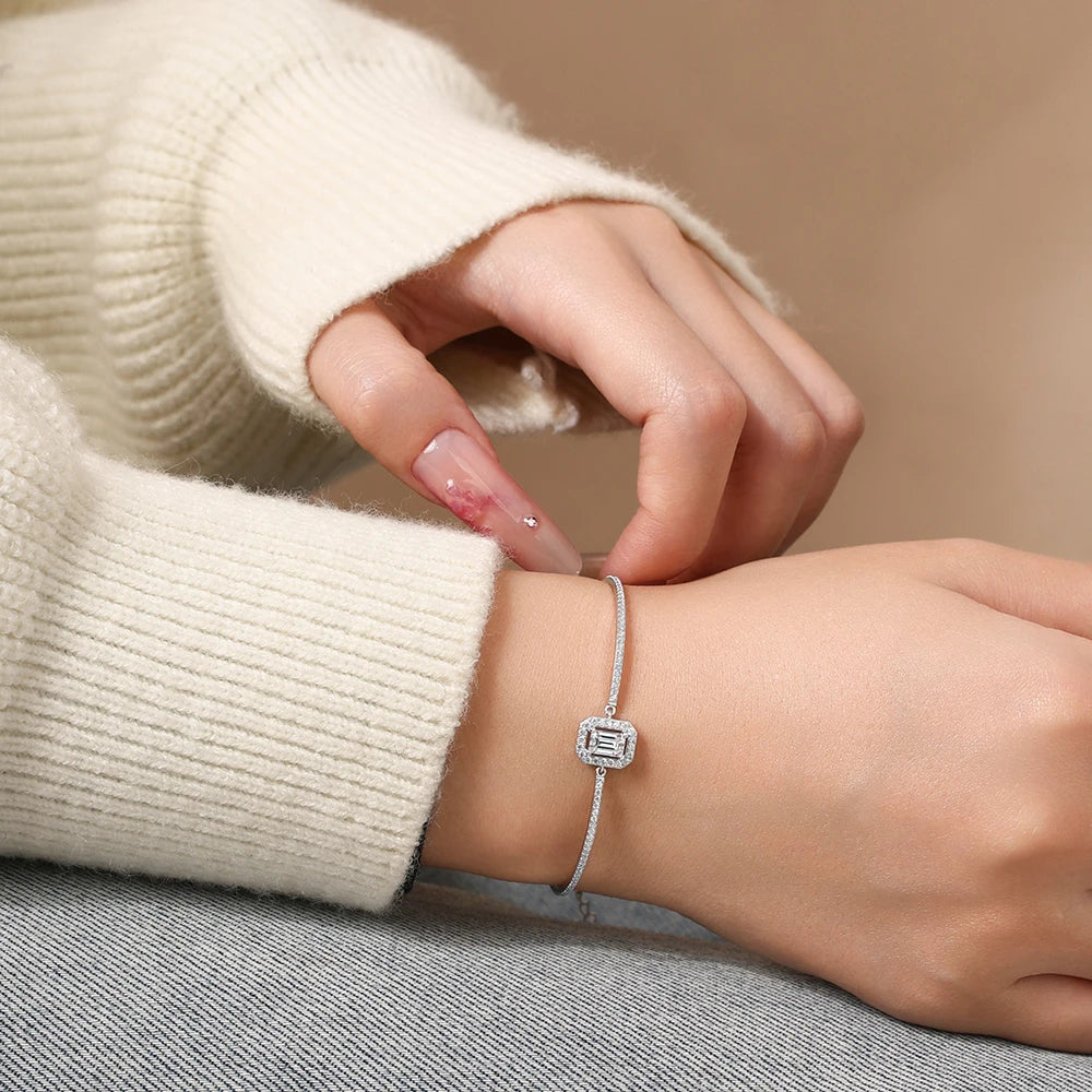 Bee-Bees emerald cut moissanite tennis bracelet in 925 sterling silver worn on a wrist with a cream sweater