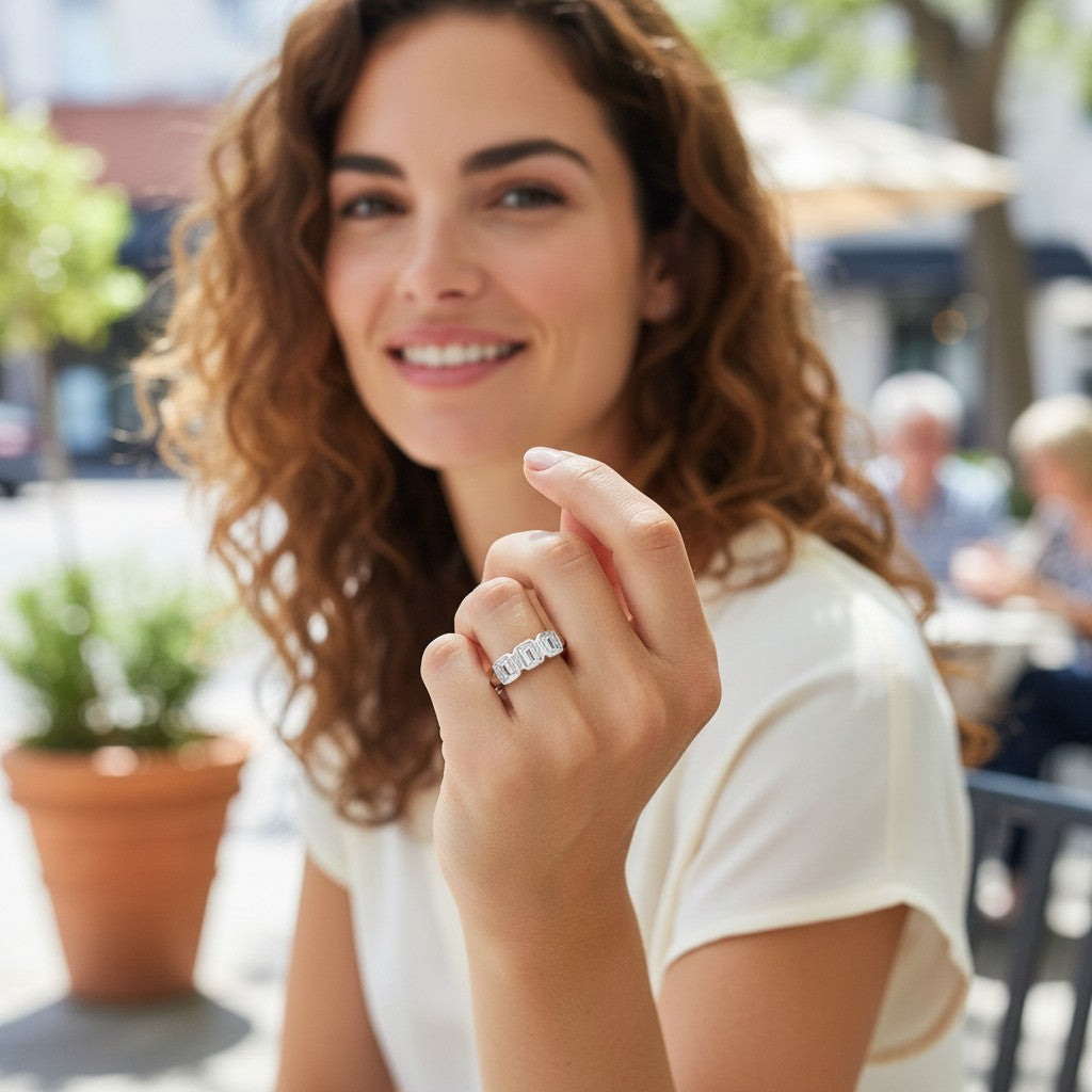 Bee-Bees 2.5ctw emerald cut moissanite 5-stone anniversary band worn by a woman in a sunny outdoor cafe setting.