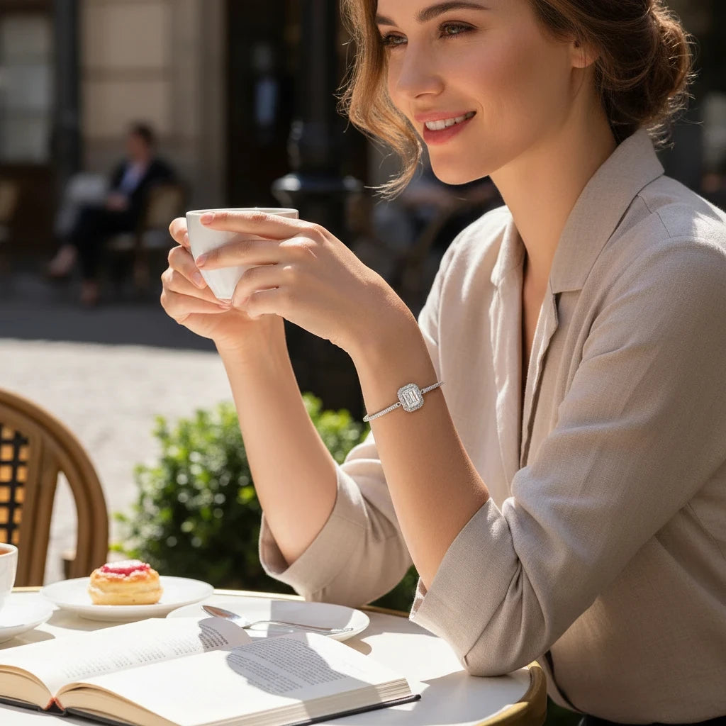 Bee-Bees emerald cut moissanite tennis bracelet in 925 sterling silver worn by a smiling woman at an outdoor cafe.