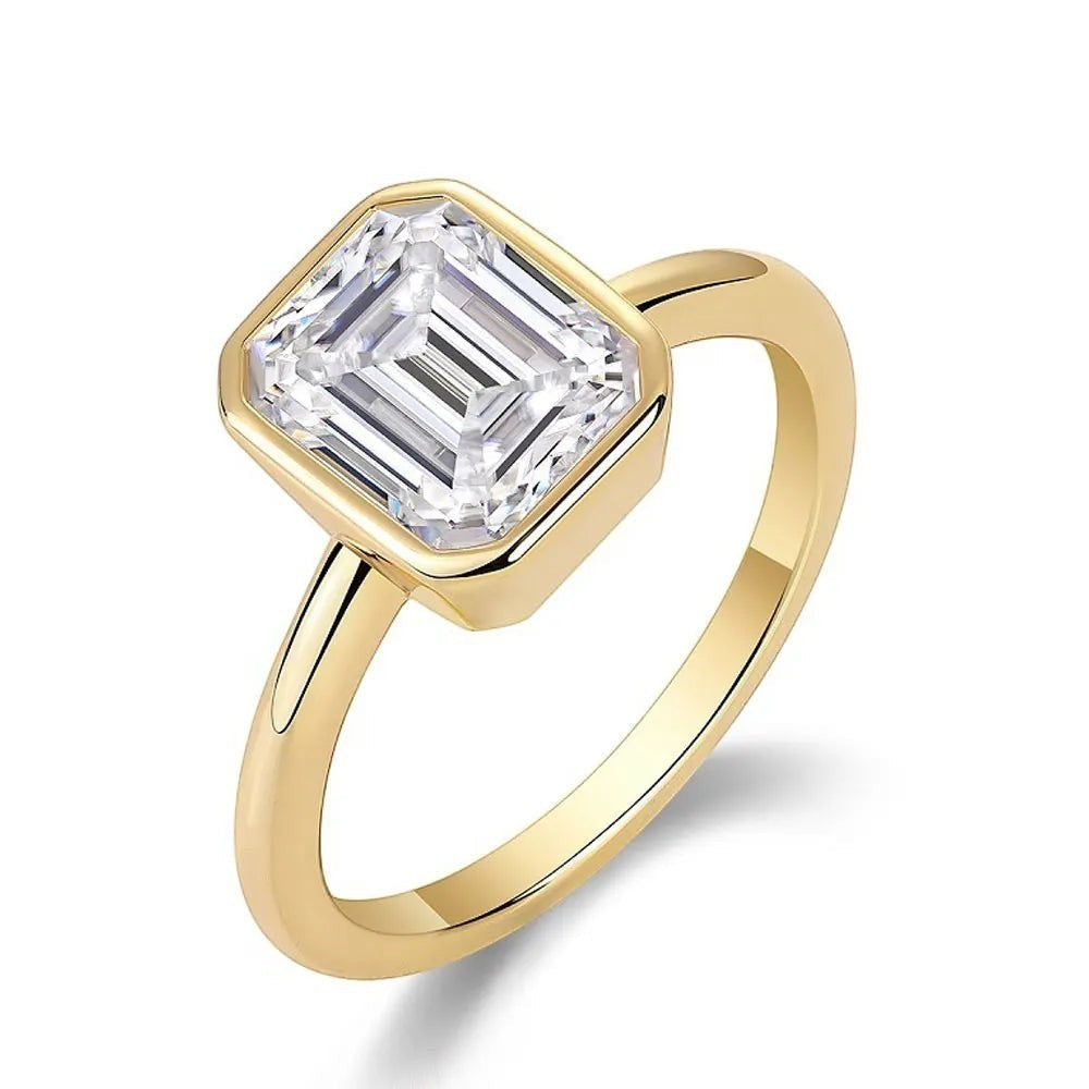 Bee-Bees 2CT emerald cut moissanite engagement ring in 18k white gold plated sterling silver with a bezel setting.