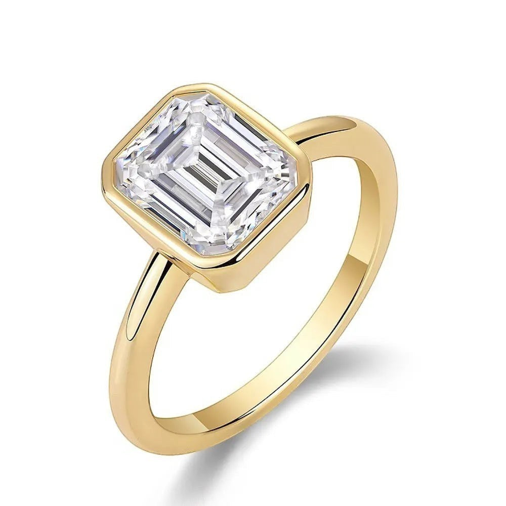 Bee-Bees 2CT emerald cut moissanite engagement ring in 18k white gold plated sterling silver with a bezel setting.