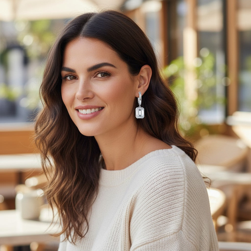 A woman wearing Bee-Bees emerald cut moissanite hoop drop earrings in 18k white gold plated sterling silver.