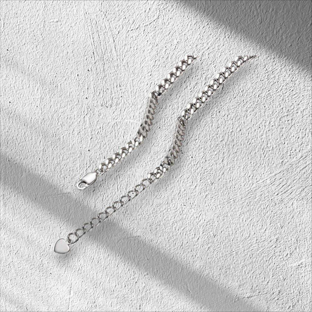 Bee-Bees Moissanite Cuban link bracelet in sterling silver with 18k white gold plating. Features adjustable length and a heart charm.