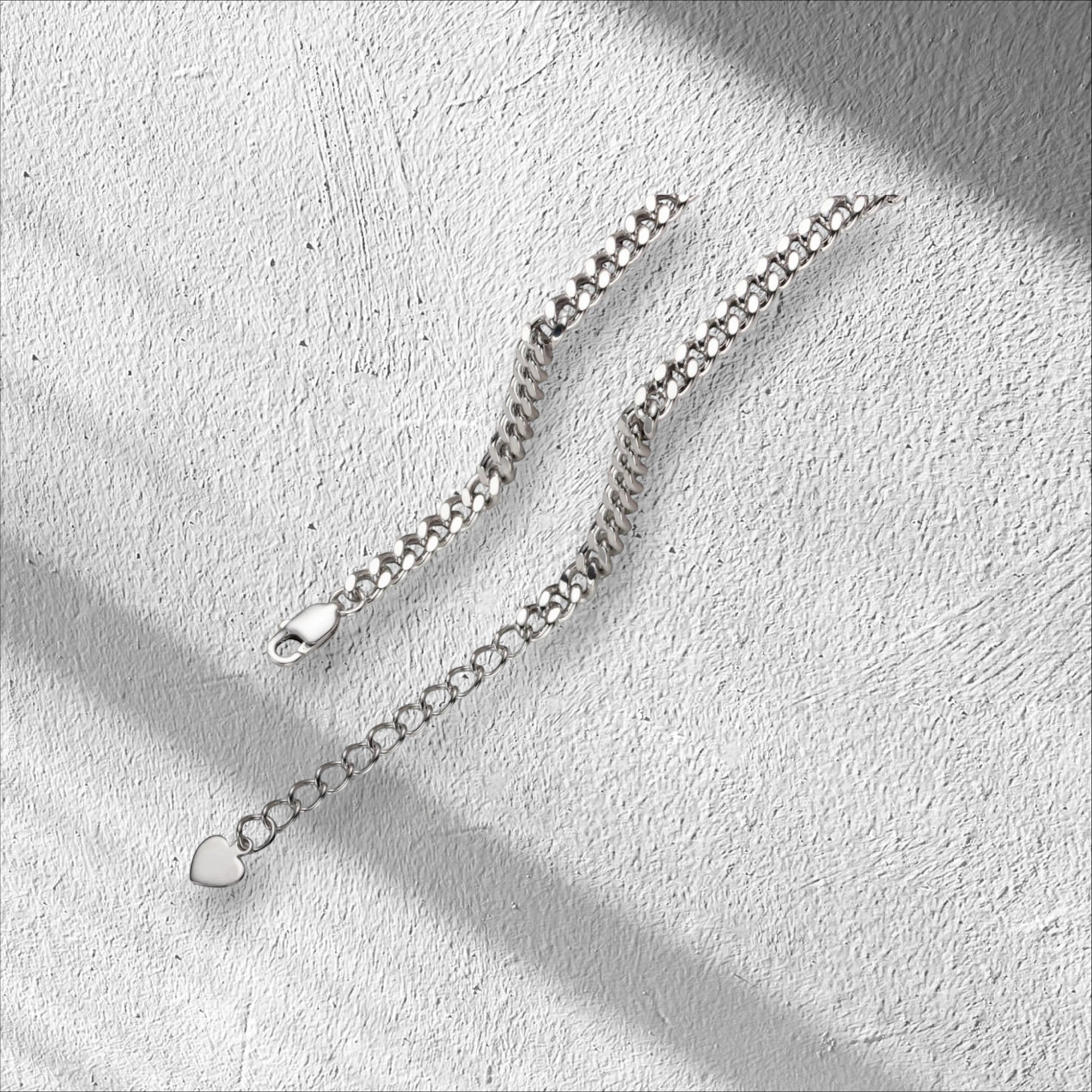 Bee-Bees Moissanite Cuban link bracelet in sterling silver with 18k white gold plating. Features adjustable length and a heart charm.