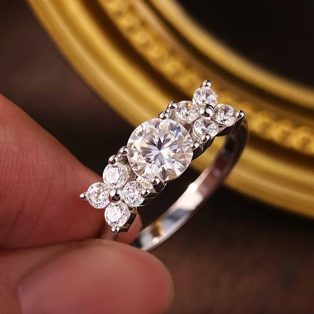 Bee-Bees 1ct D VVS1 Moissanite engagement ring in 925 silver with 18k white gold plating. Round brilliant cut center stone with smaller stones.