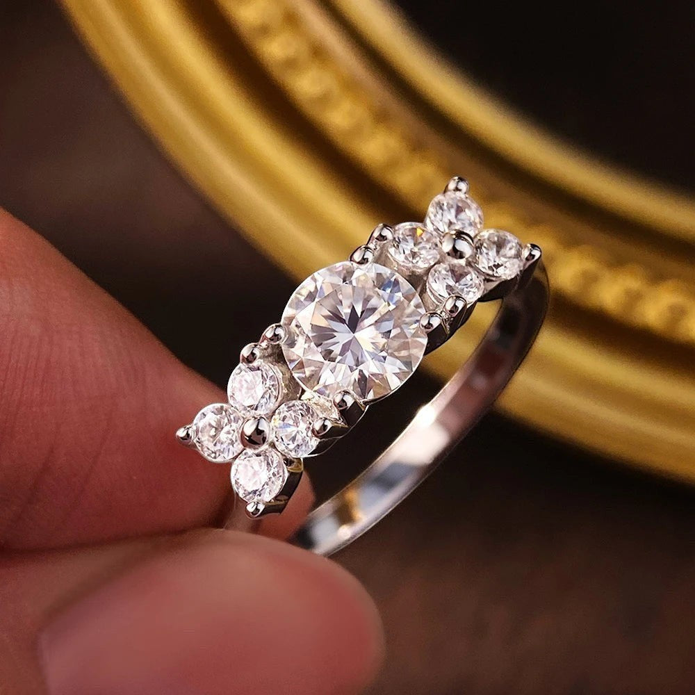 Bee-Bees 1ct D VVS1 Moissanite engagement ring in 925 silver with 18k white gold plating. Round brilliant cut center stone with smaller stones.