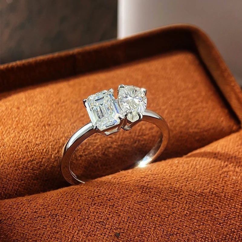 Bee-Bees 1ct/2ct D VVS1 Moissanite engagement ring in S925 silver with 18K white gold plating, featuring two stones: emerald and pear cut.