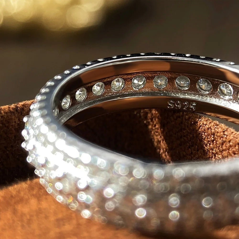 Bee-Bees Moissanite eternity band ring in s925 Sterling Silver with 18k white gold plating. Features round-cut stones and "S925" stamp.
