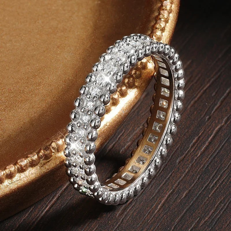 Bee-Bees VVS1 Moissanite full eternity wedding band in sterling silver with 18k white gold plating. Features round brilliant cut stones and a beaded edge.