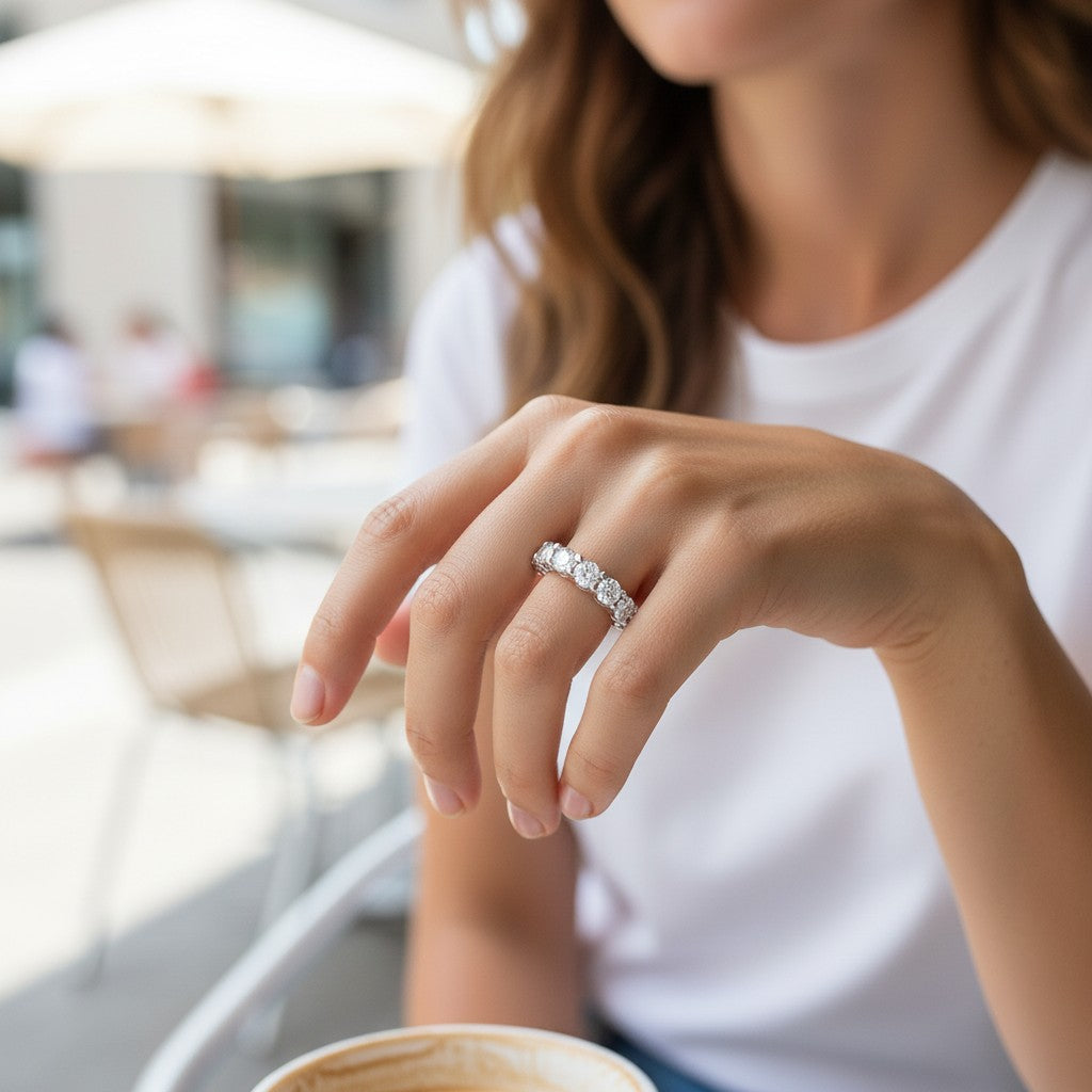 Bee-Bees full eternity moissanite band in 925 sterling silver worn on a woman's finger at an outdoor cafe.