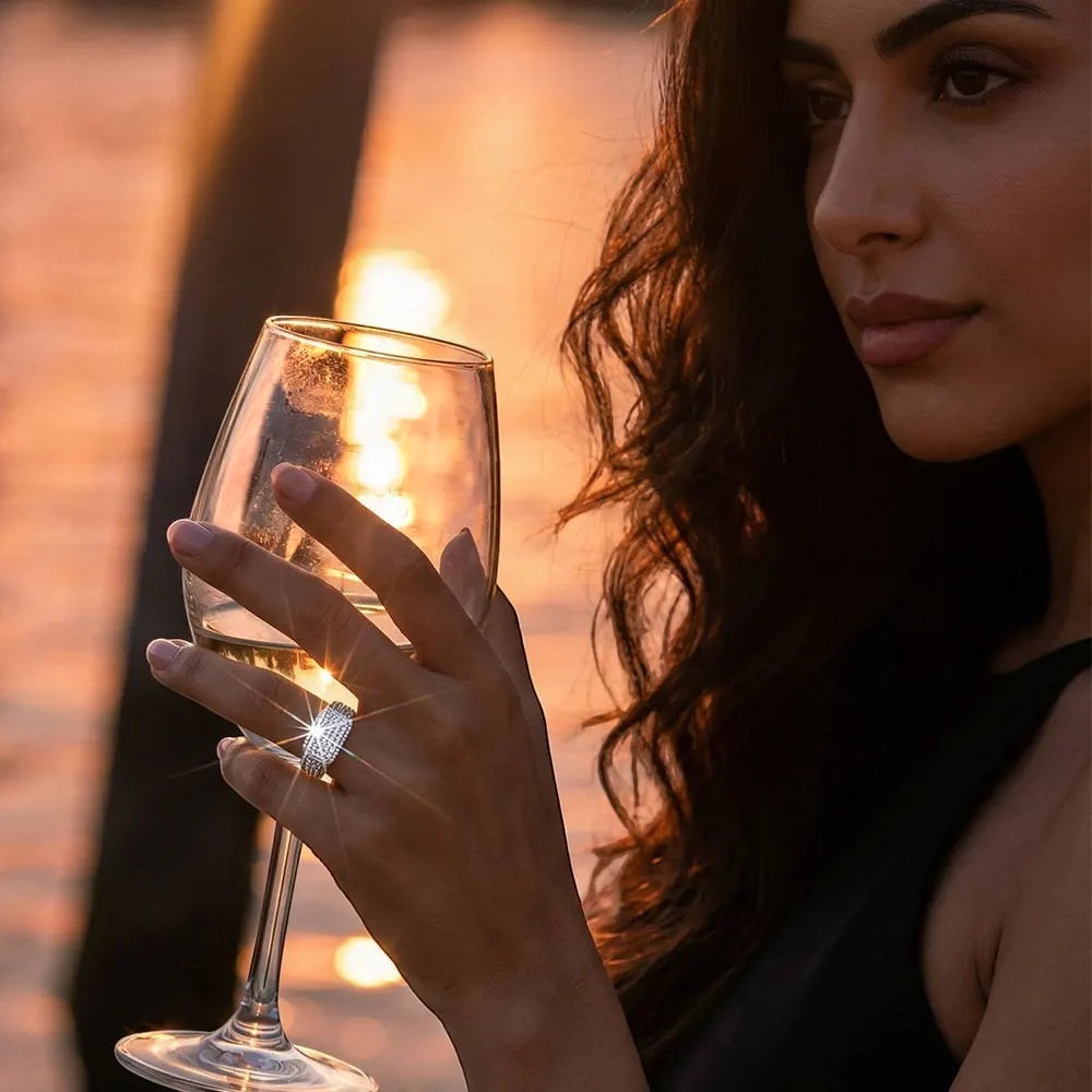 Bee-Bee's D VVS Moissanite eternity ring in 18k white gold plated 925 silver, worn by a woman holding a wine glass at sunset.
