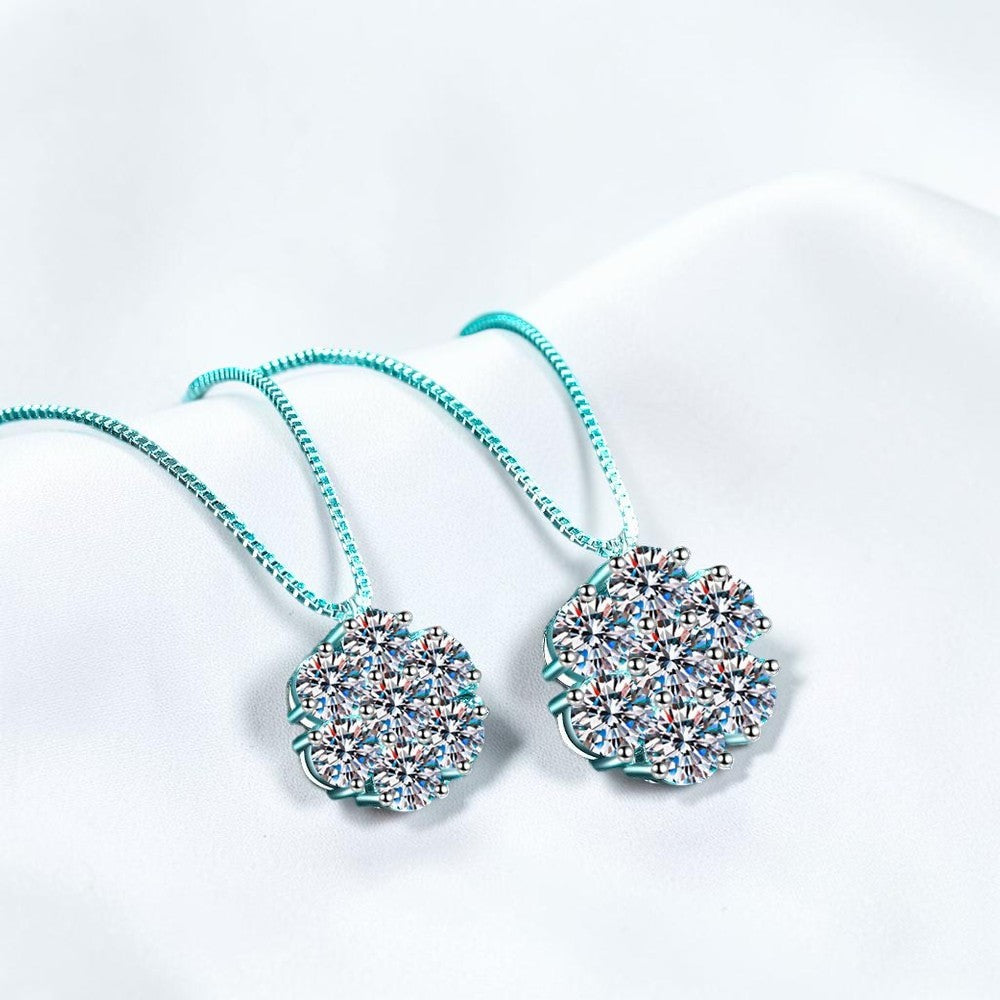 Bee-Bees moissanite flower pendant necklaces in 925 sterling silver with 18k white gold plating on a teal background.