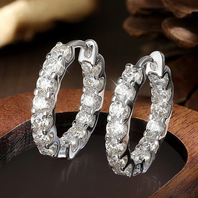 Bee-Bees 2.6ctw D Color Moissanite eternity hoop earrings in 18k white gold plated sterling silver. Round brilliant cut stones.