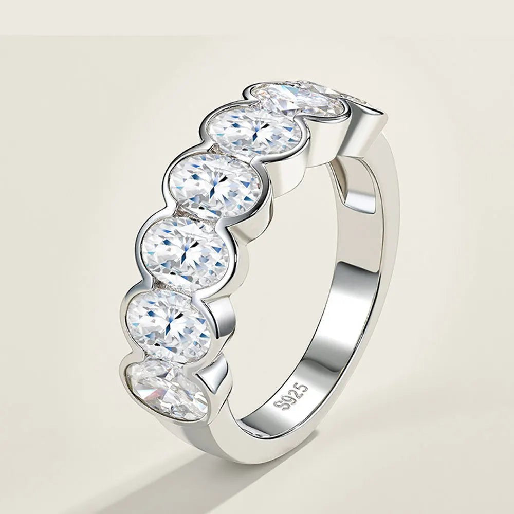 Bee-Bees 0.5ct oval-cut moissanite eternity band in 18k white gold plated sterling silver with shared-prong setting.