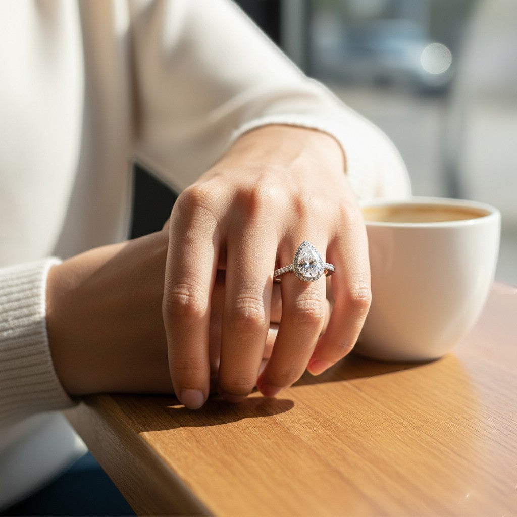 Bee-Bees 2.0CT pear cut moissanite engagement ring on a woman's finger, featuring a 925 sterling silver band.
