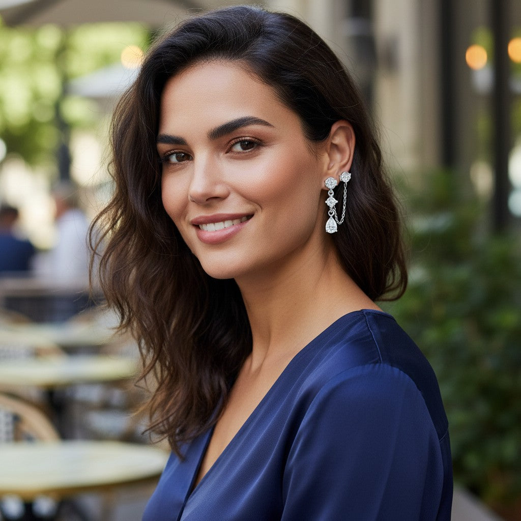 Bee-Bees pear-cut moissanite drop earrings in sterling silver worn by a woman in a navy blue dress