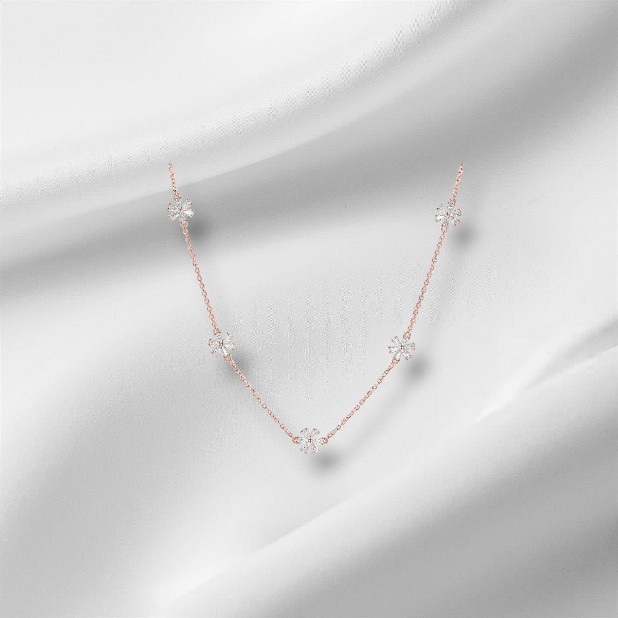 Bee-Bee's rose gold sterling silver necklace with five small flower charms, each set with sparkling moissanite stones.