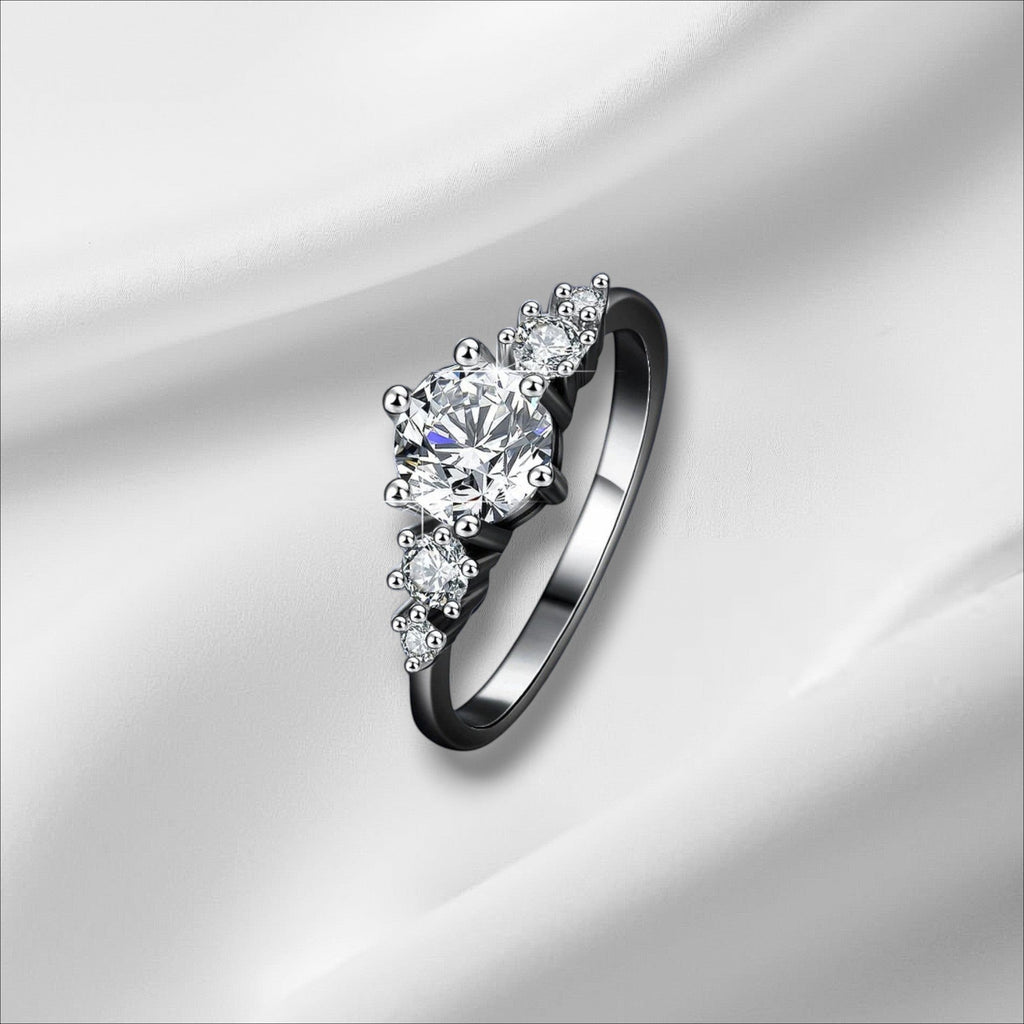 Bee-Bees 1ct round moissanite engagement ring in s925 sterling silver with 18k white gold plating. Features a central solitaire stone with smaller accent stones.
