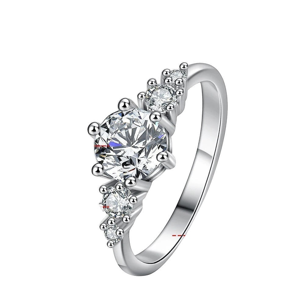Bee-Bees 1ct round moissanite engagement ring in sterling silver with 18k white gold plating. Features a solitaire stone with accent stones.