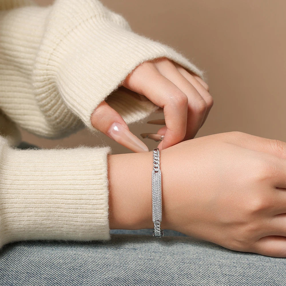 Bee-Bees sterling silver Cuban link bangle featuring sparkling D color VVS1 moissanite stones on a woman's wrist.